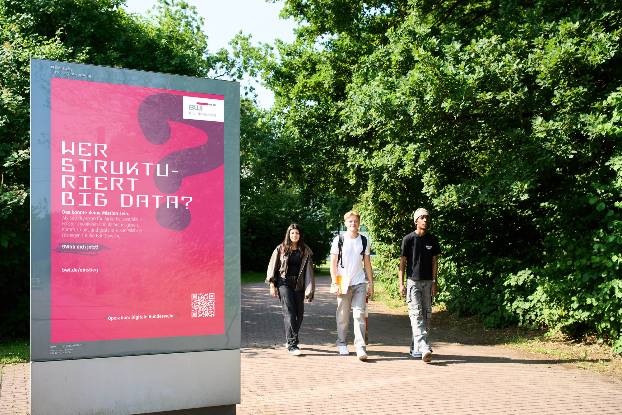Studierende gehen auf ein City-Light-Poster (CLP) an der Universit&auml;t D&uuml;sseldorf zu