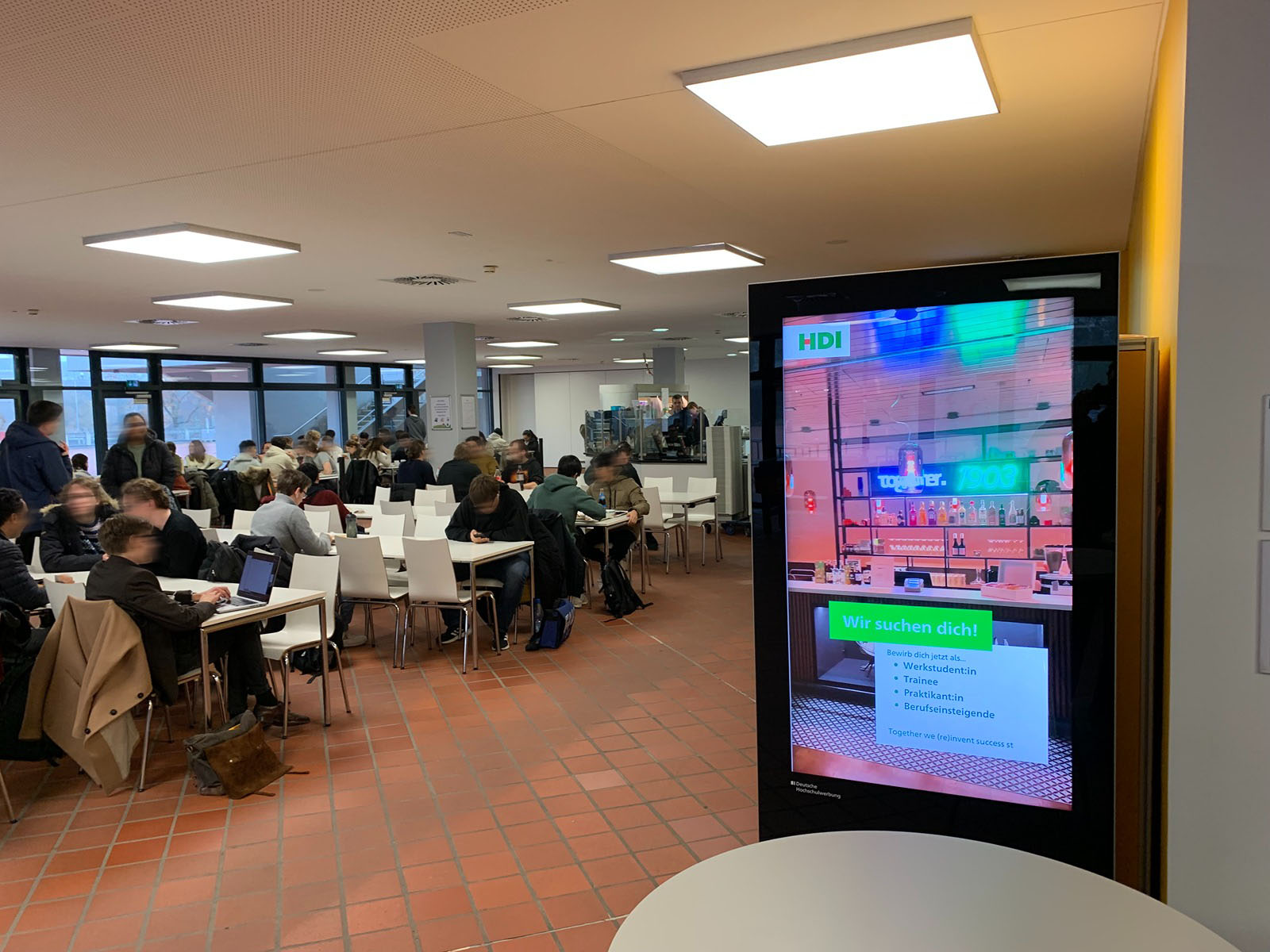DOOH in the cafeteria: vertical screen next to seating areas ensures long viewing time